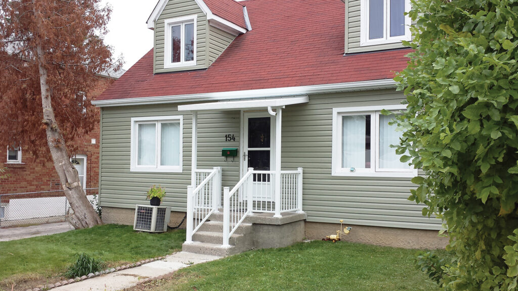 Custom Deck Builder for Homeowners - M2 Decks & Enclosures A small white structural aluminum patio cover installed over a front door entry with white railings on a green siding home.