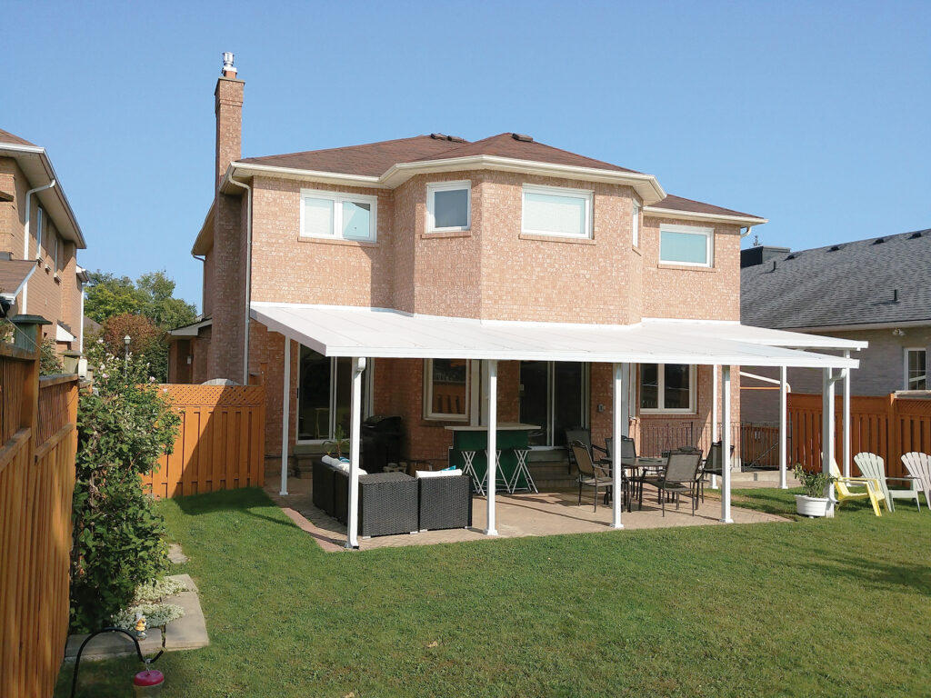 Custom Deck Builder for Homeowners - M2 Decks & Enclosures A large white structural aluminum patio cover with a solid insulated roof installed over a backyard paver patio on a brick home.