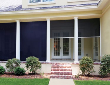 Custom Deck Builder for Homeowners - M2 Decks & Enclosures Exterior view of a home patio featuring white pillars and three motorized screens, one fully lowered and two partially lowered to show captured-edge sealing.