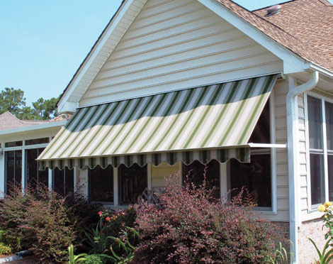 Custom Deck Builder for Homeowners - M2 Decks & Enclosures A green and tan striped retractable window awning installed on a tan siding home to provide shade and energy savings.