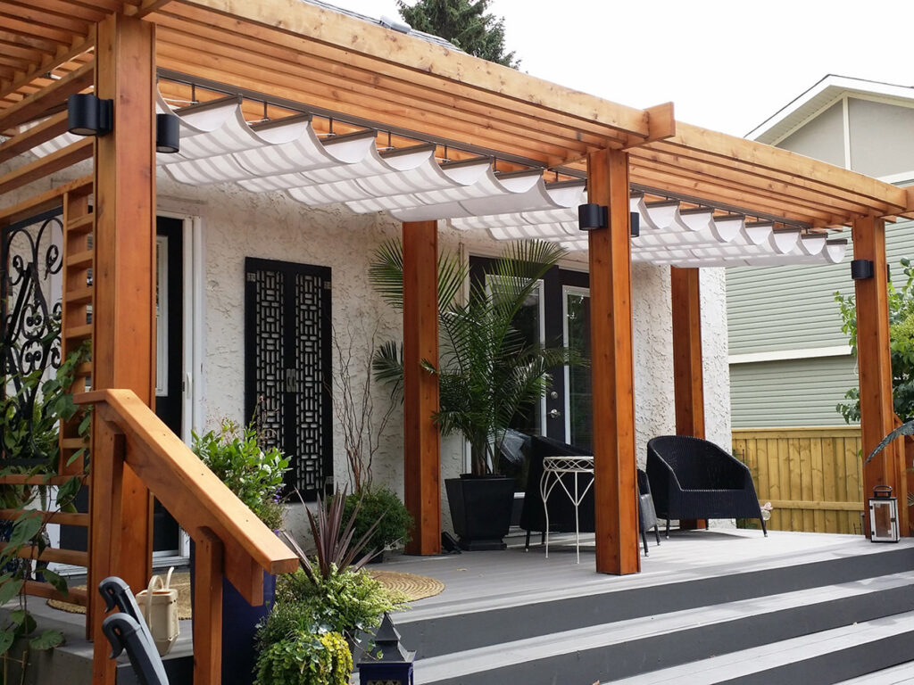 A large cedar wood pergola on a modern grey deck featuring an integrated white retractable fabric canopy system for adjustable patio shade.