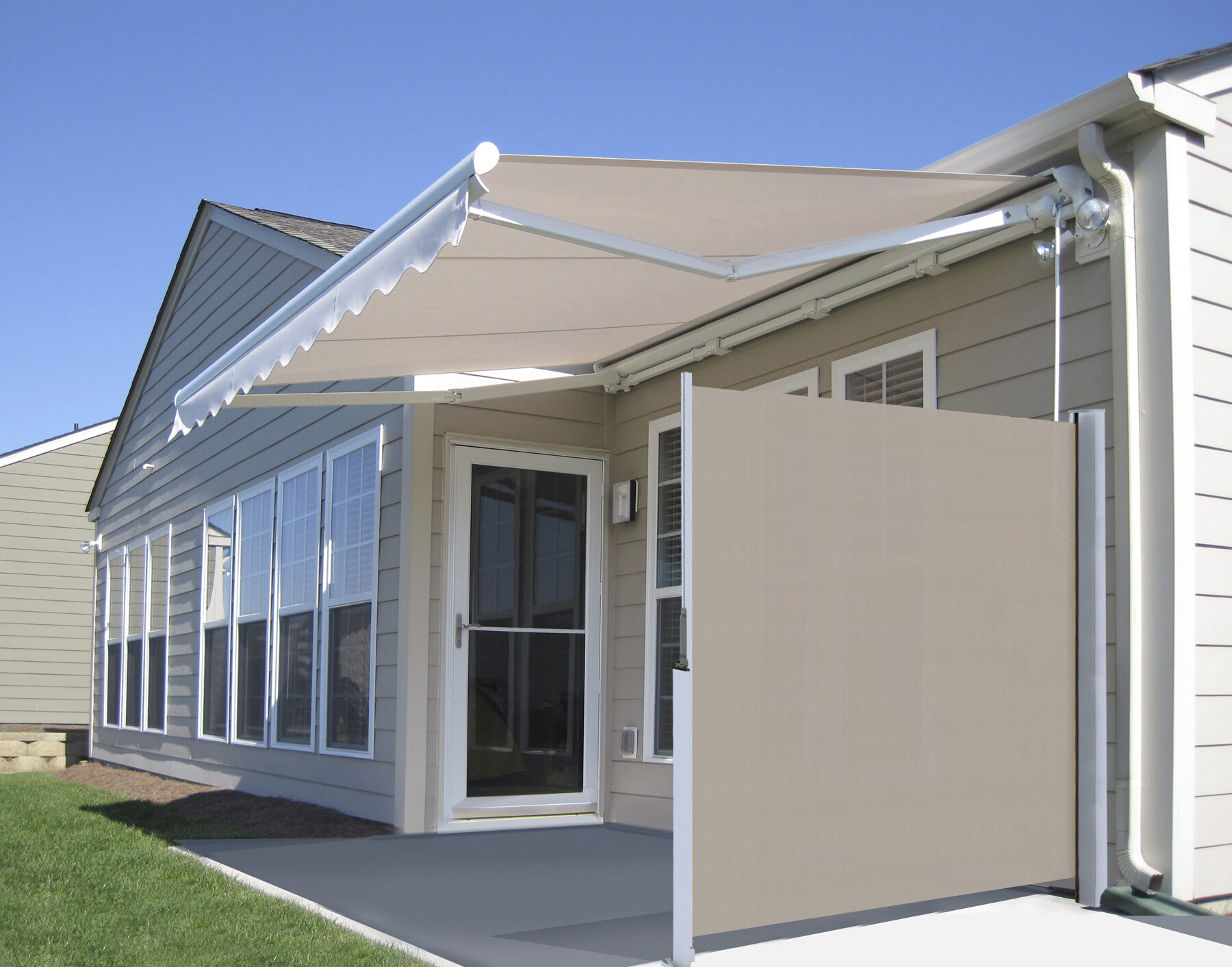 A tan manual horizontal side shade extended to provide privacy on a patio, shown alongside a matching retractable awning on a tan siding home.
