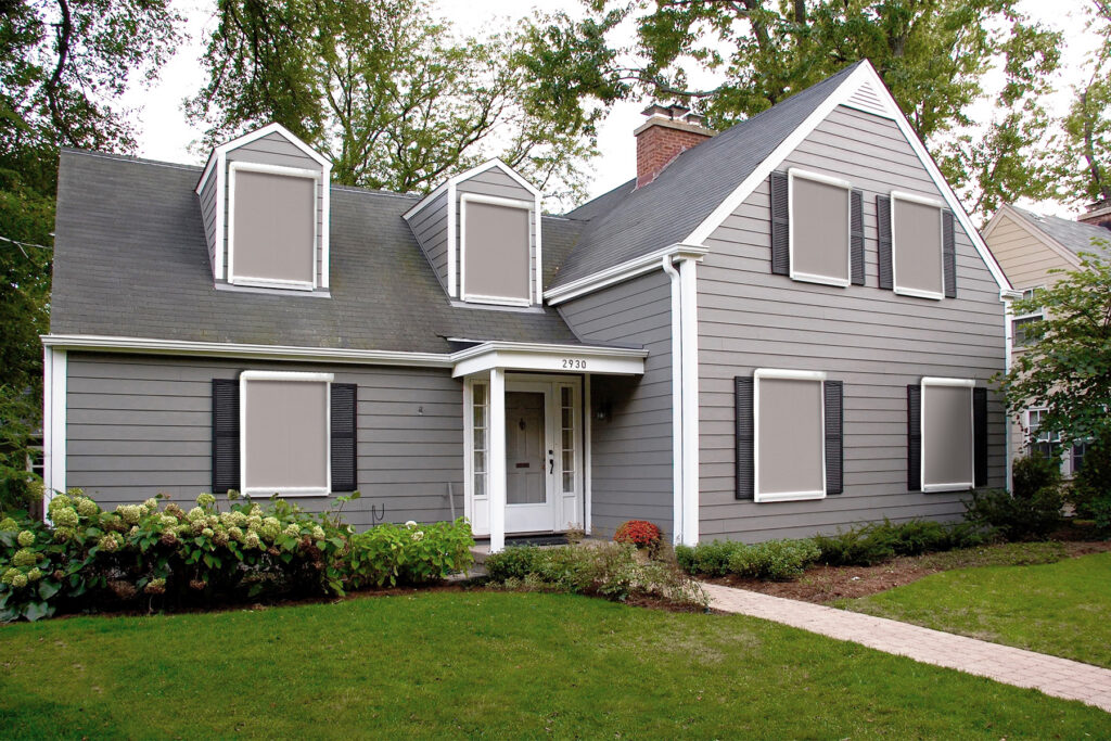 Custom Deck Builder for Homeowners - M2 Decks & Enclosures Exterior of a grey two-story home with multiple motorized solar shades installed on both upper-floor dormers and main-floor windows for automated sun control.