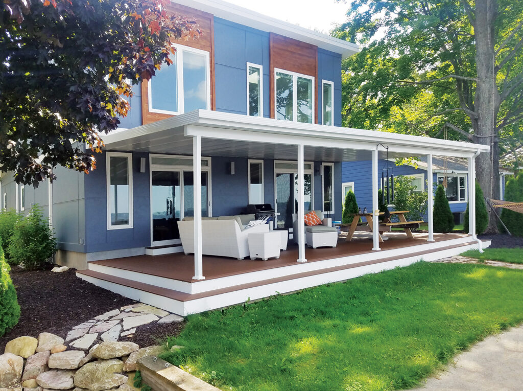 Custom Deck Builder for Homeowners - M2 Decks & Enclosures A wide, modern white structural aluminum patio cover with an insulated roof system installed over a large composite deck on a blue and wood-accented home.
